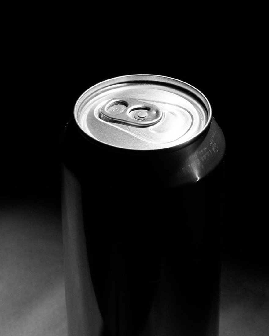 VANTA — a single matte-black aluminium can set down on a dark plate under one cold raking light, a serial struck into its matte shell, the auction lot in expensive silence